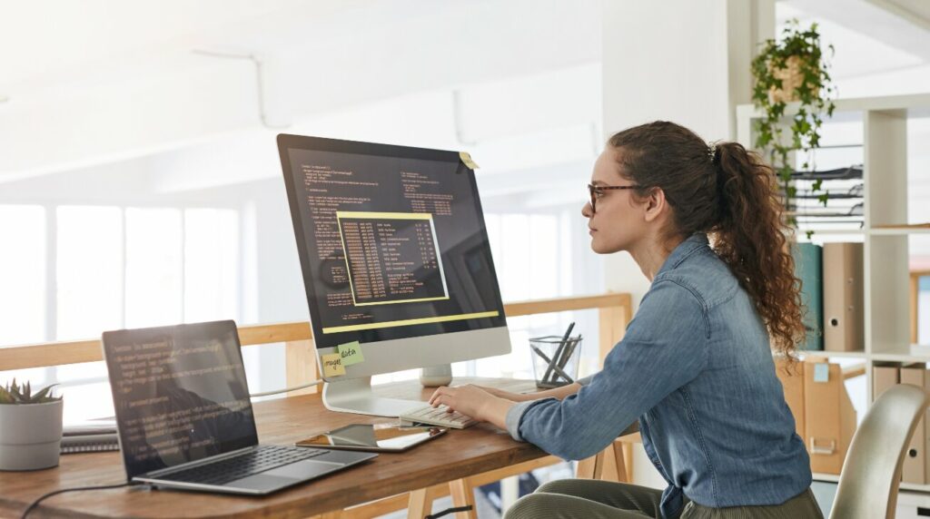 Woman working on computer and laptop